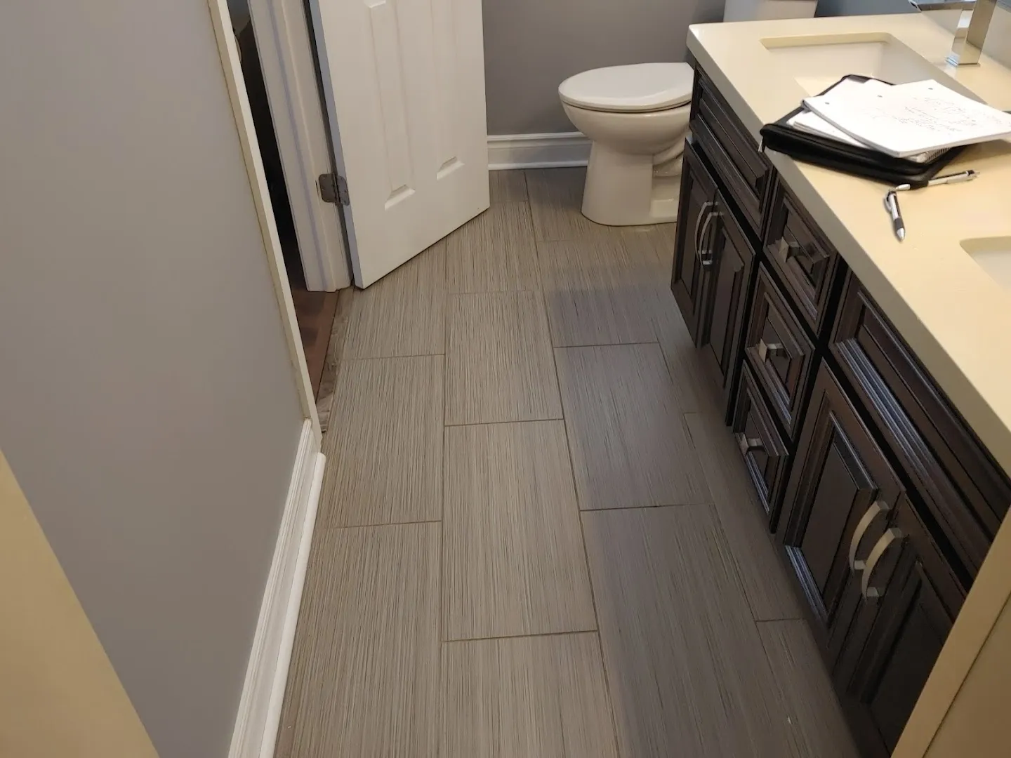 Newly renovated bathroom with dark flooring, white fixtures, and updated finishes after restoration