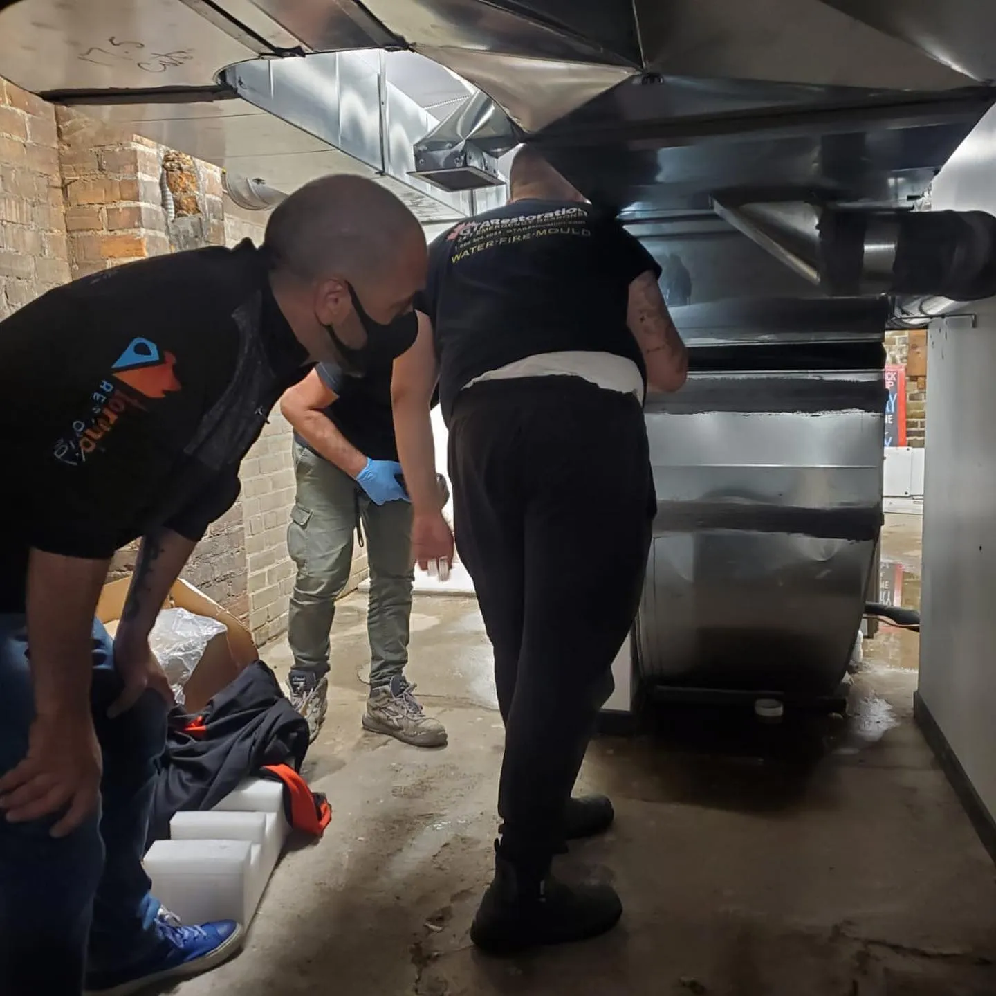 Water restoration team managing commercial extraction equipment during basement flood cleanup