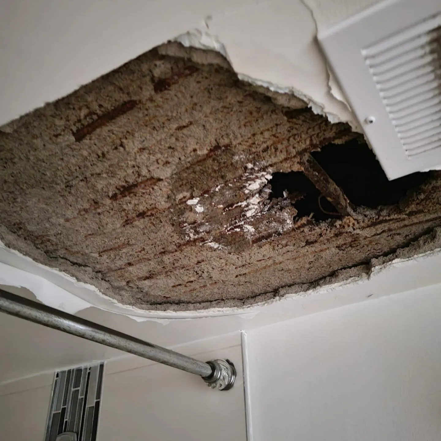 Exposed ceiling cavity showing damaged insulation and debris from water damage remediation