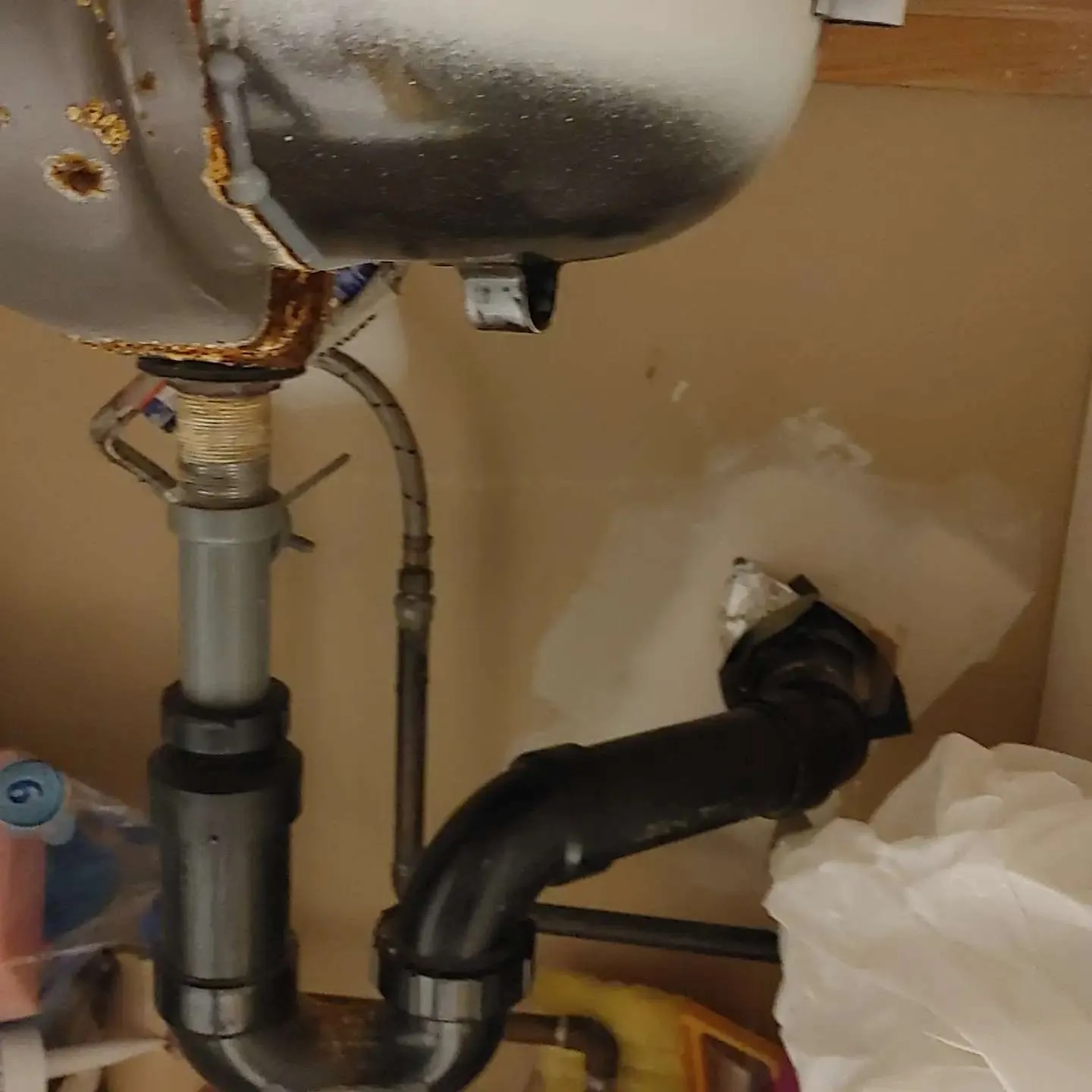 Bathroom sink plumbing showing corroded pipes, mineral buildup, and water damage evidence from continuous leaking